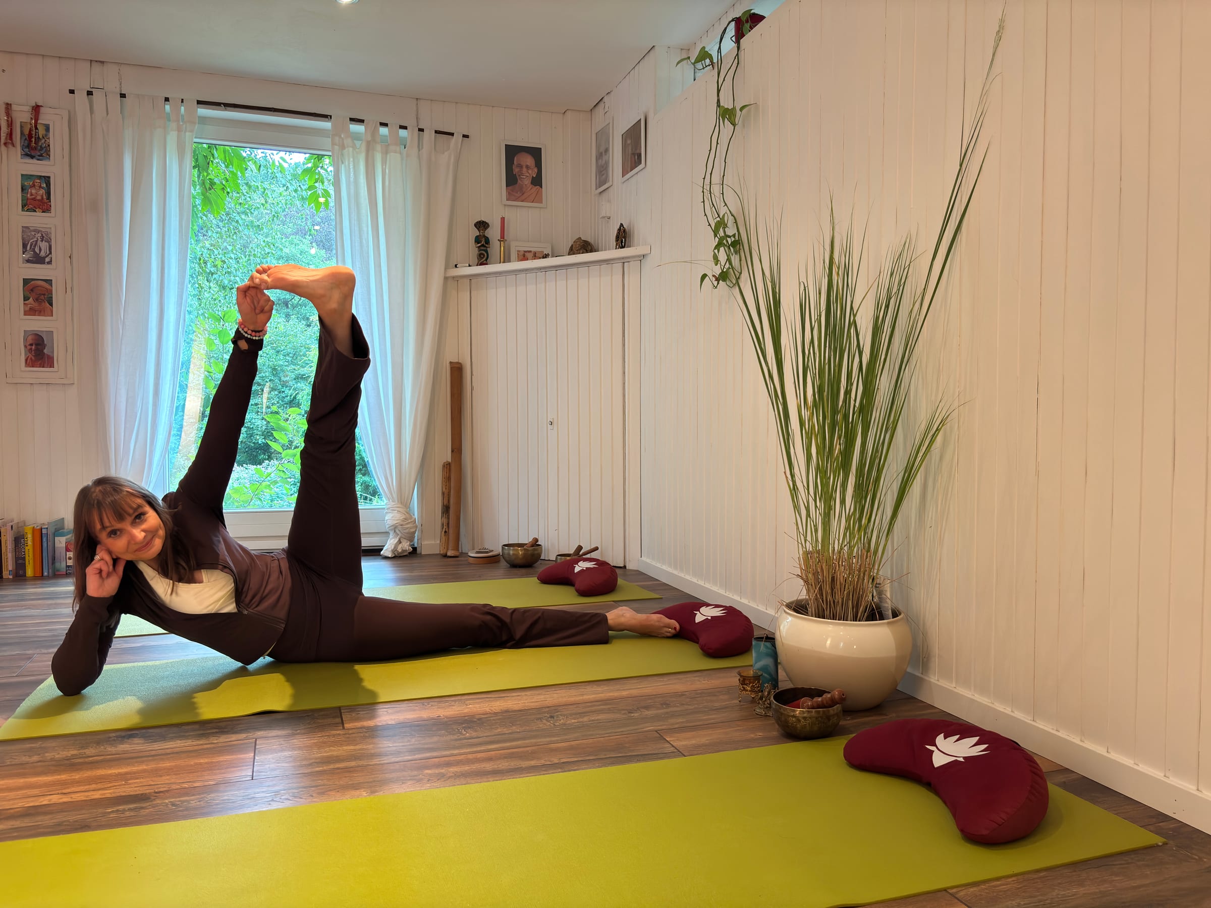 Sabine Stratmann lächelnd in einer Yogahaltung in ihrem Studio in Herdecke
